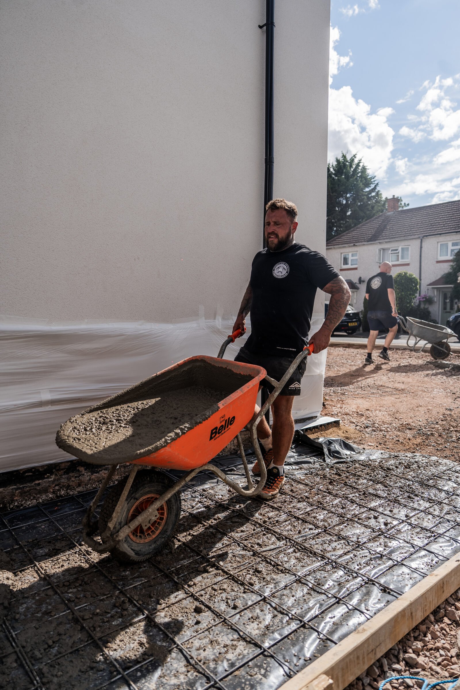 Fresh concrete being moved by wheelbarrow over driveway reinforcement